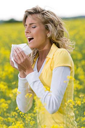 Women sneezing with Hay fever in a field of flowers